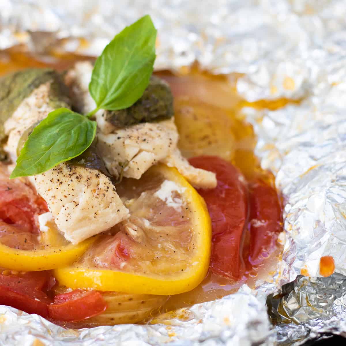 an opened foil pack after cooking, topped with basil