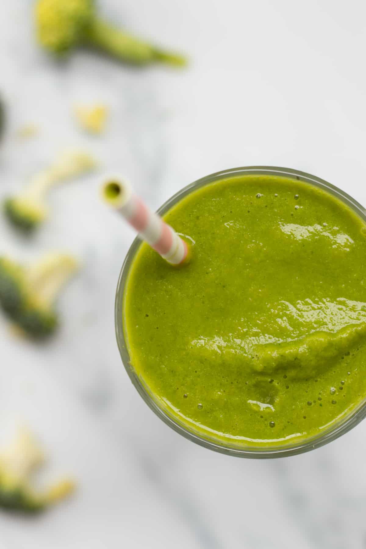 top down view of a green broccoli smoothie with broccoli next to it