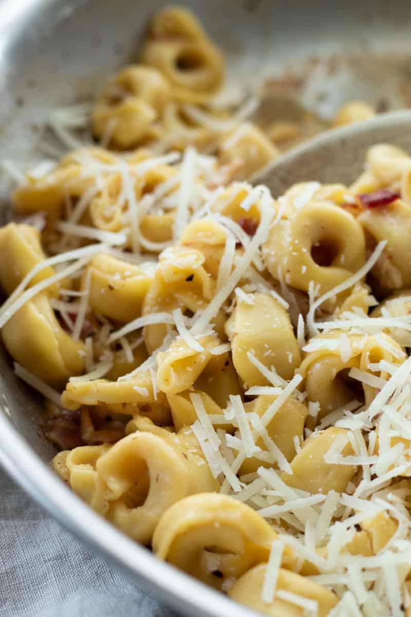 close-up of tortellini carbonara topped with cheese