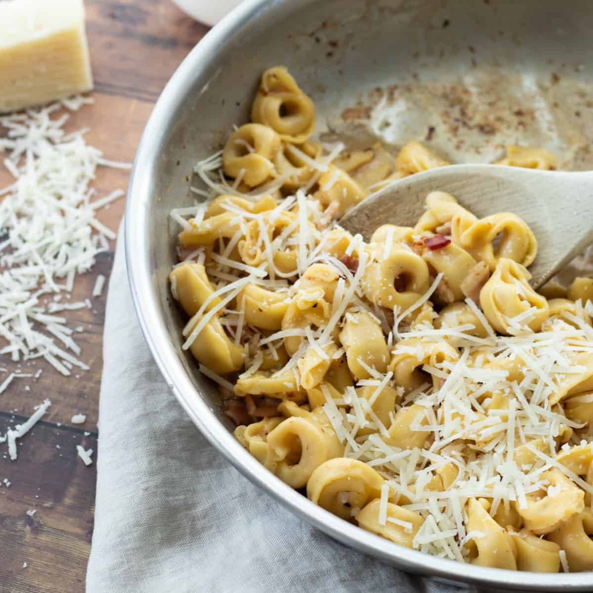 tortellini carbonara in a pan topped with cheese