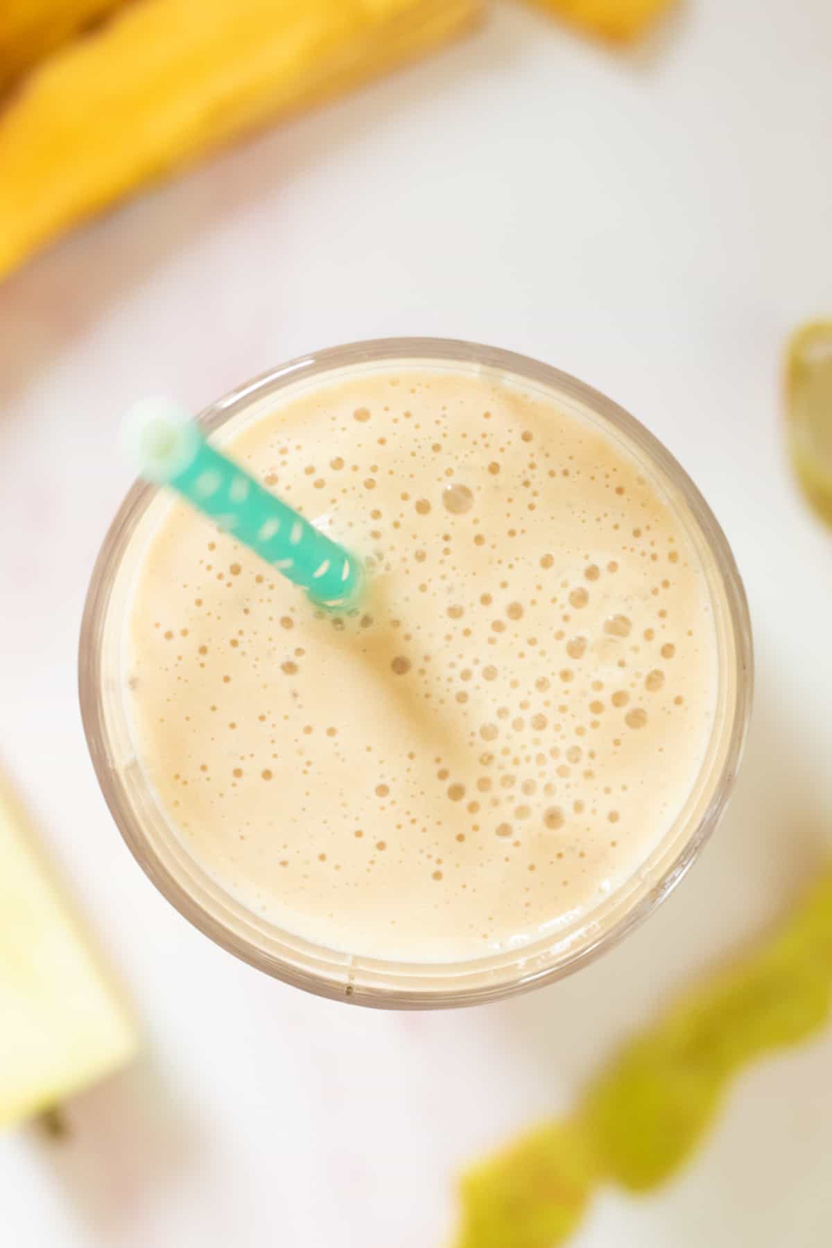 top down view of an apple banan smoothie with a blue straw