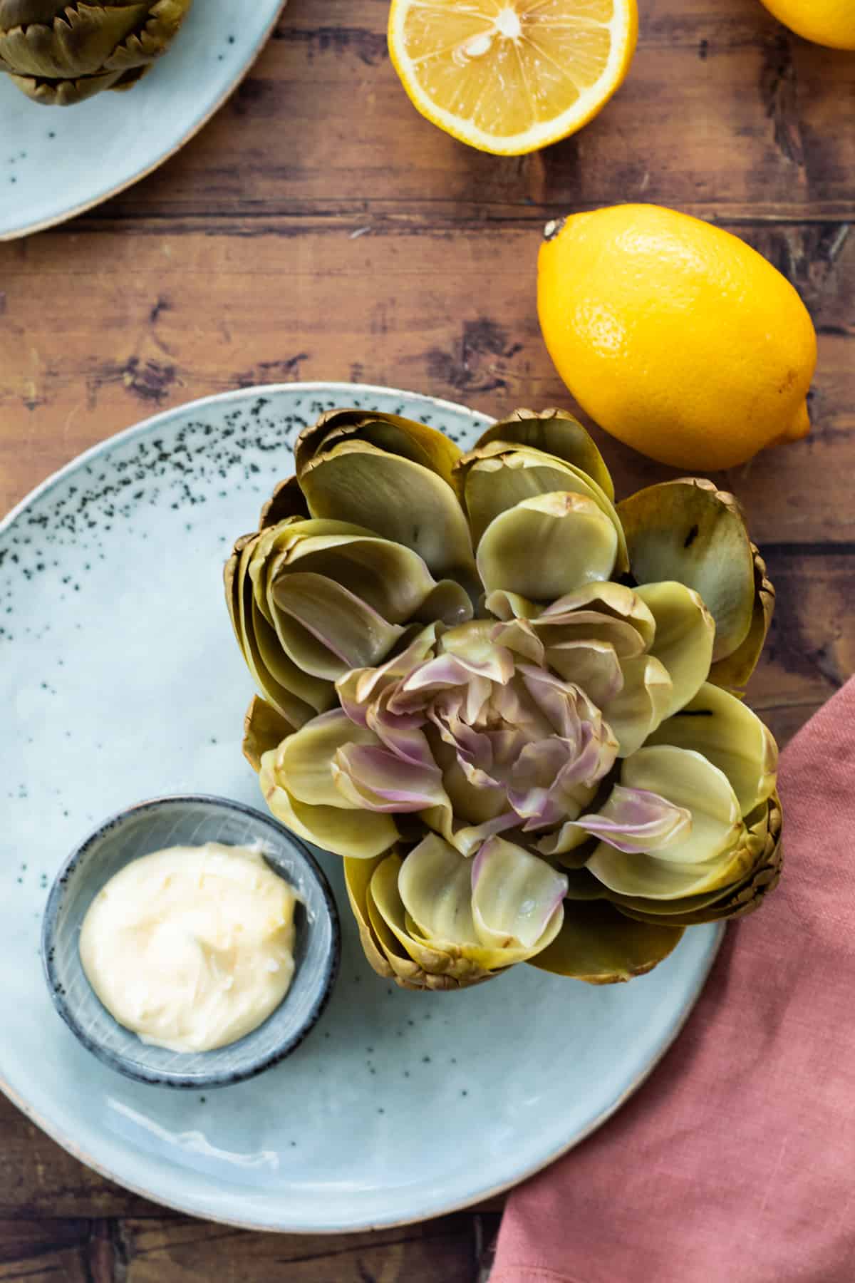 top down view of an opened artichoke on a blue plate