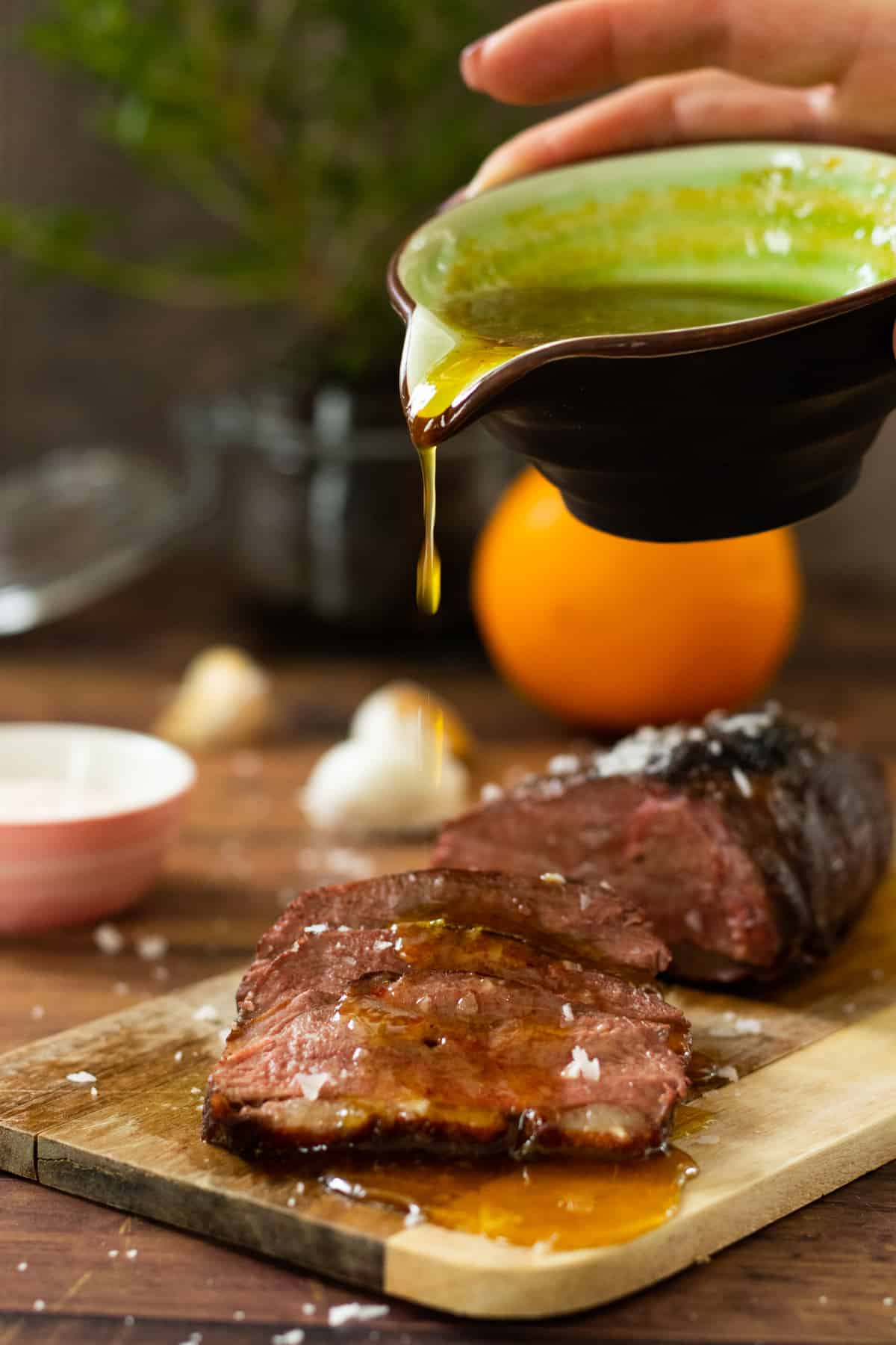 orange sauce being poured over sliced duck breast.