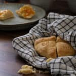 scones in a kitchen towel with some scones topped with marmalade in the background