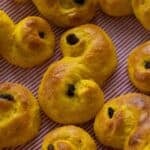 Golden lussekatter on a red and white striped kitchen towel.