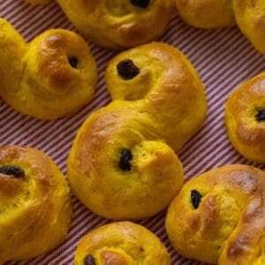 Golden lussekatter on a red and white striped kitchen towel.