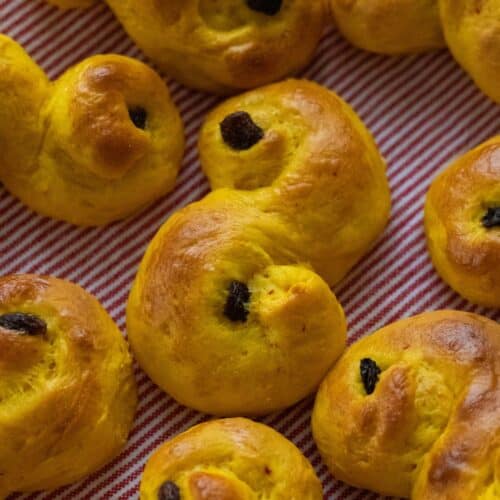 Golden lussekatter on a red and white striped kitchen towel.