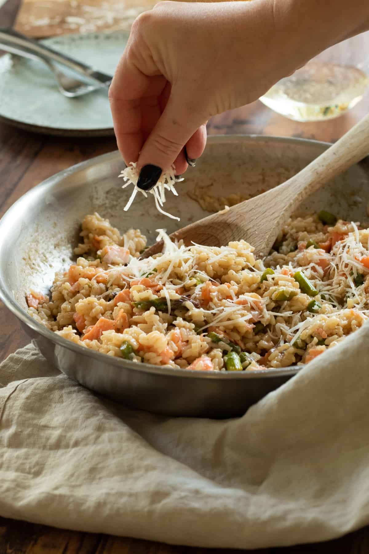 a smoked salmon risotto being topped with parmesan.
