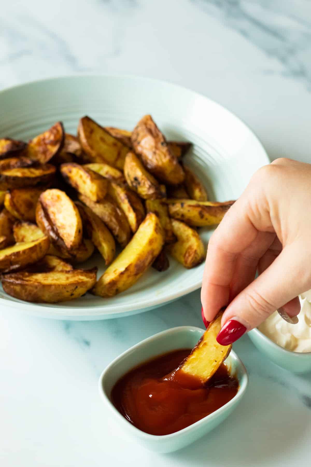 a potato wedge being dipped in ketchup