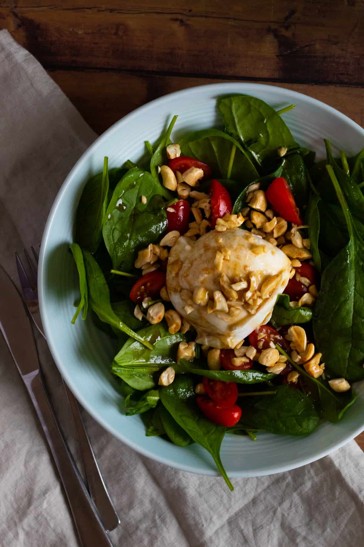 top down view of a burrata caprese salad topped with cashew nuts