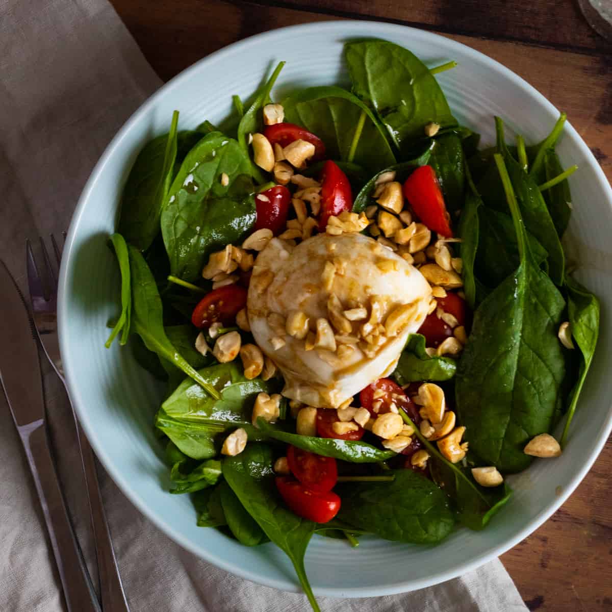 top down view of a burrata caprese salad on a light blue deep plate