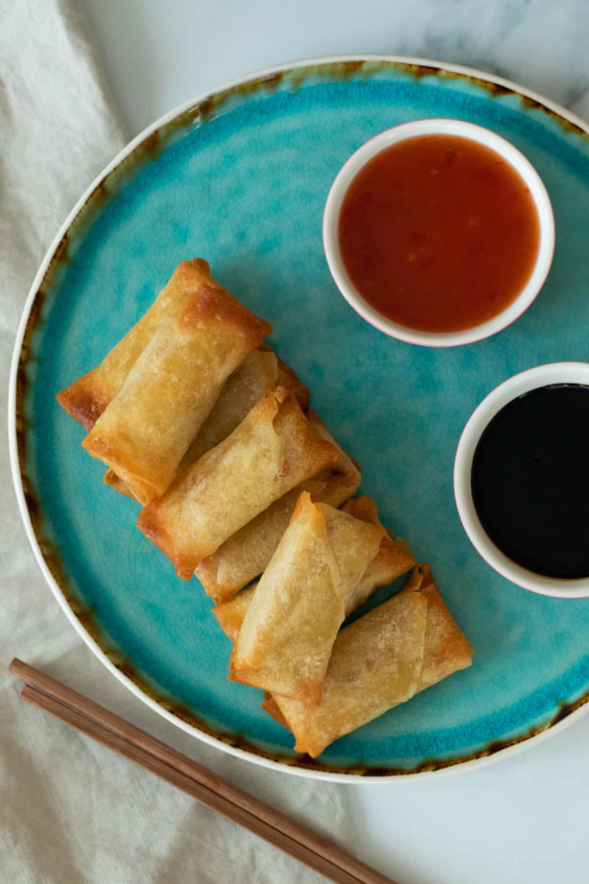 air fryer spring rolls on a blue plate next to two sauces