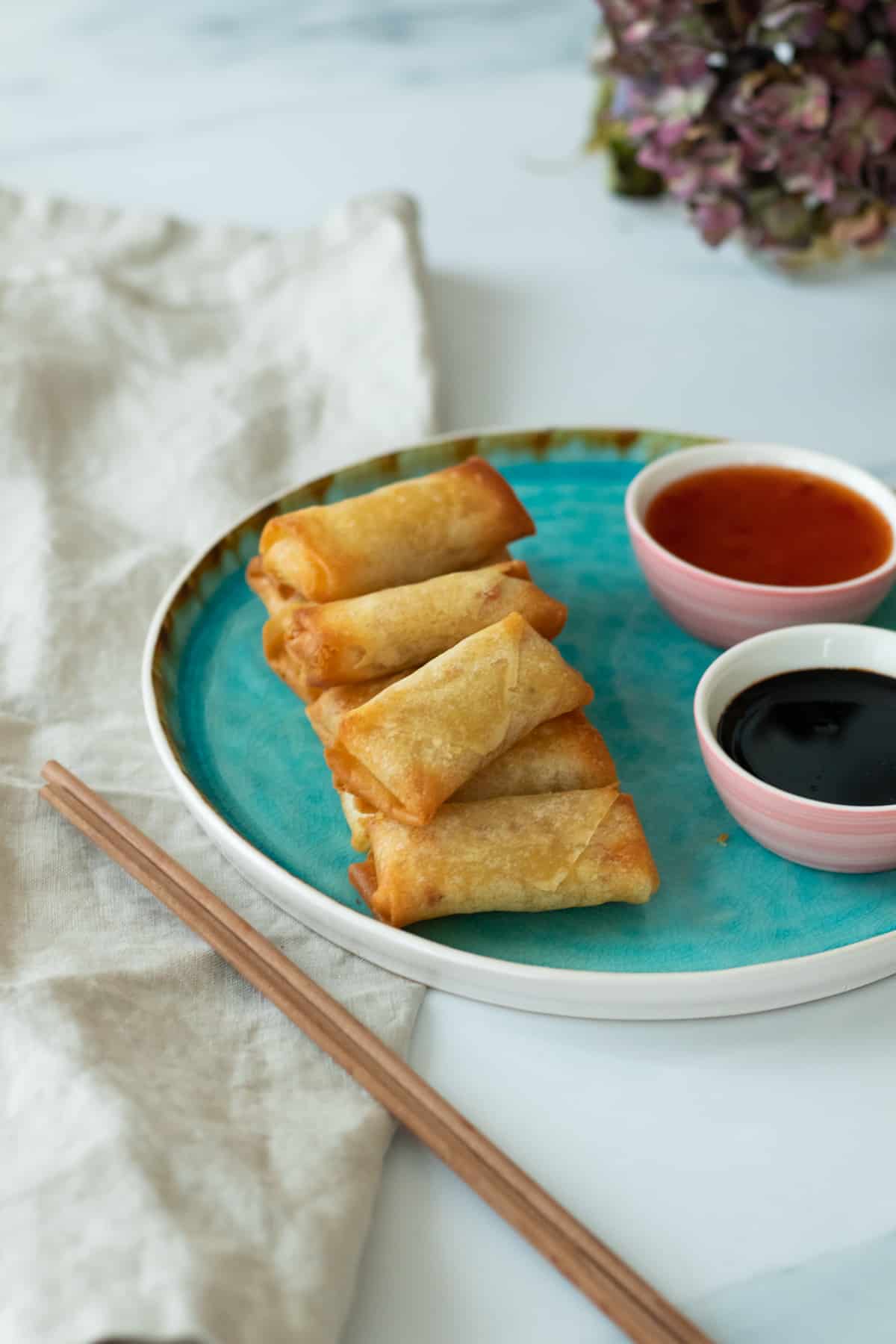 air fryer spring rolls on a blue plate next to two sauces