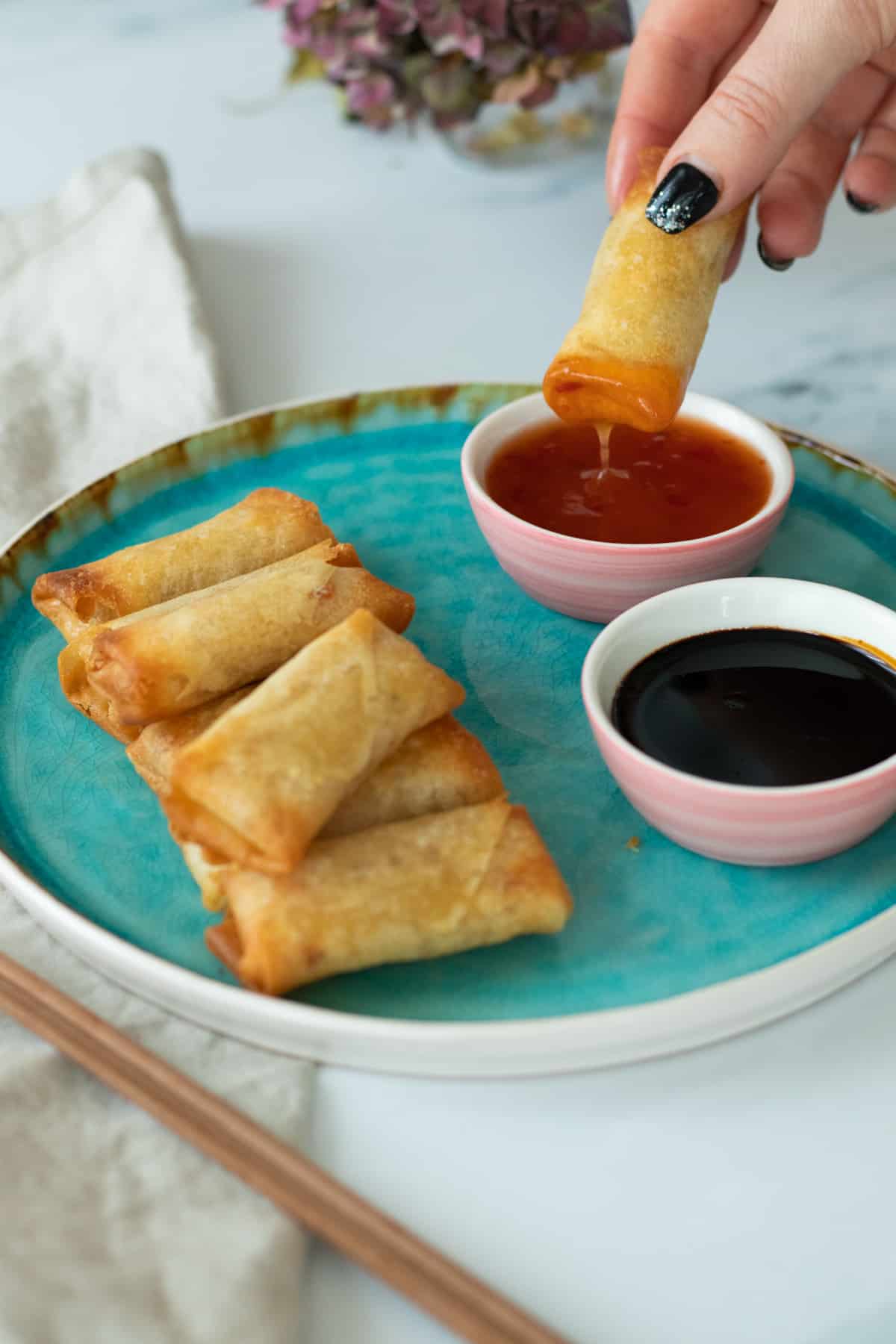 a spring roll being dipped in sauce