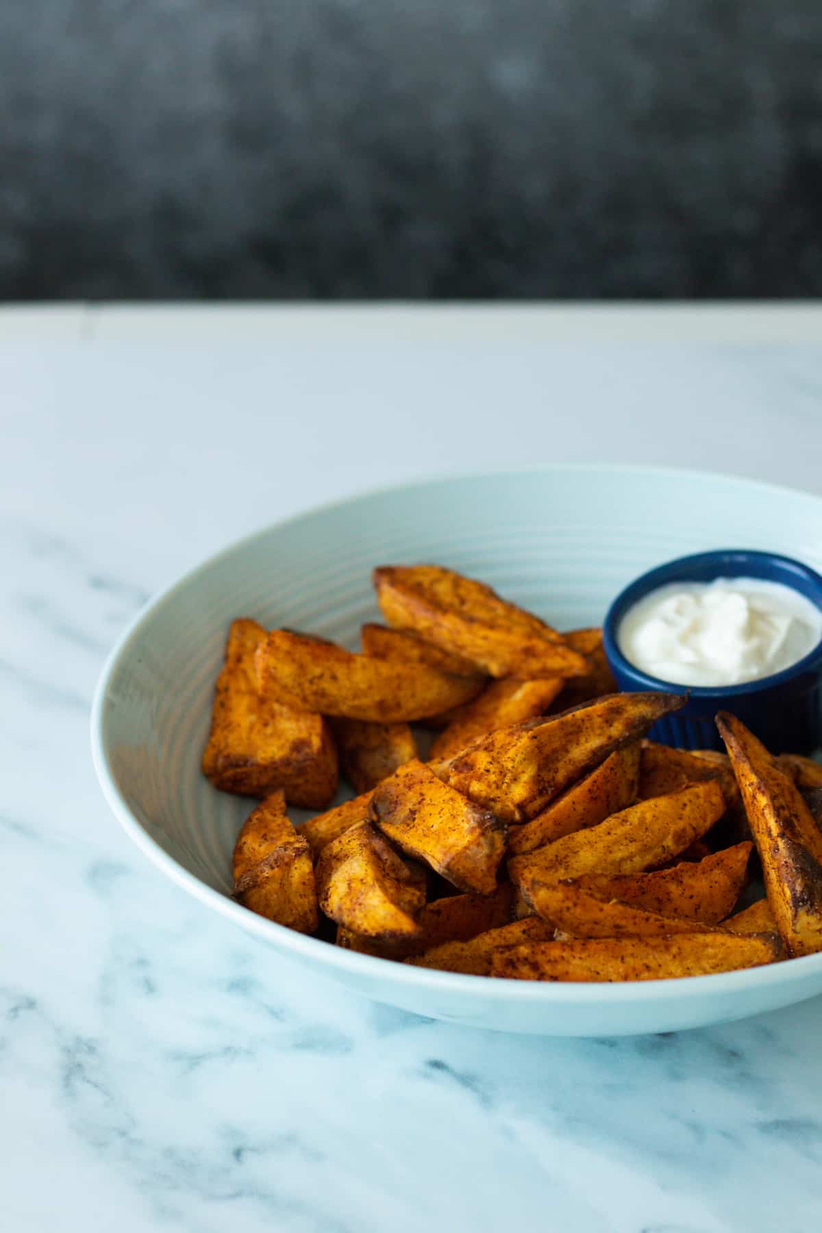 air fryer sweet potatoes on a plate with a white dip