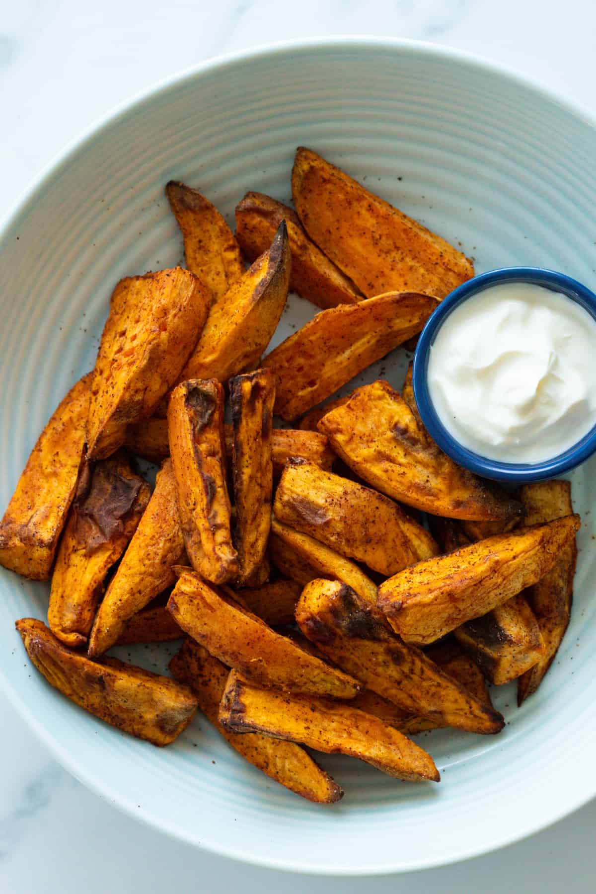 air fryer sweet potatoes on a plate with a white dip