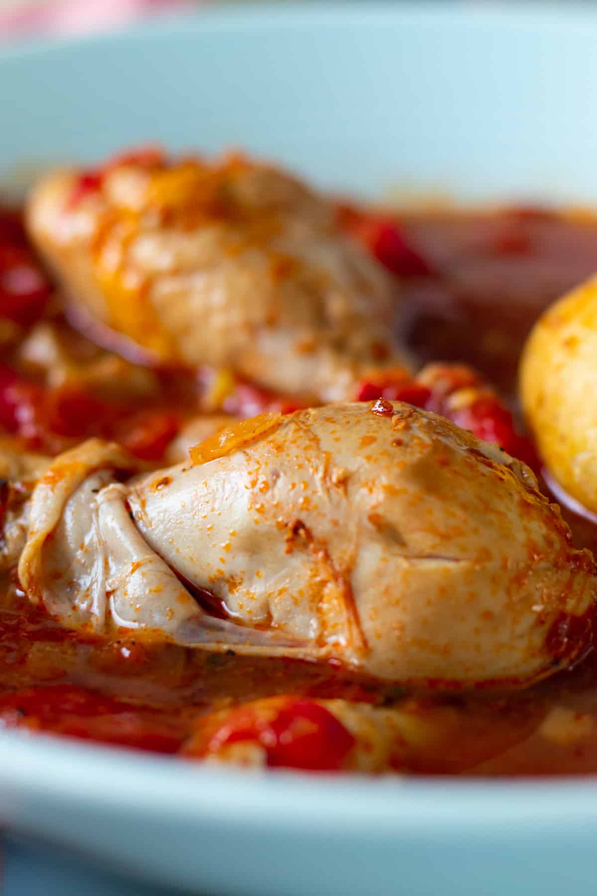 close up of a chicken drumstick in tomato sauce