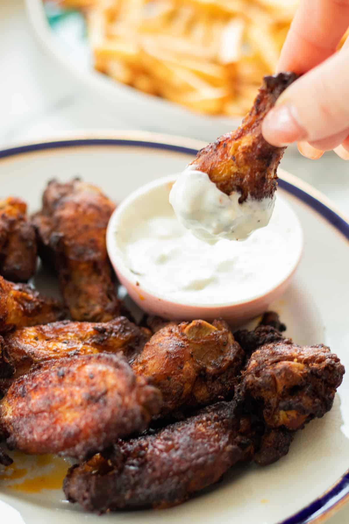 a chicken wing being dipped into blue cheese sauce