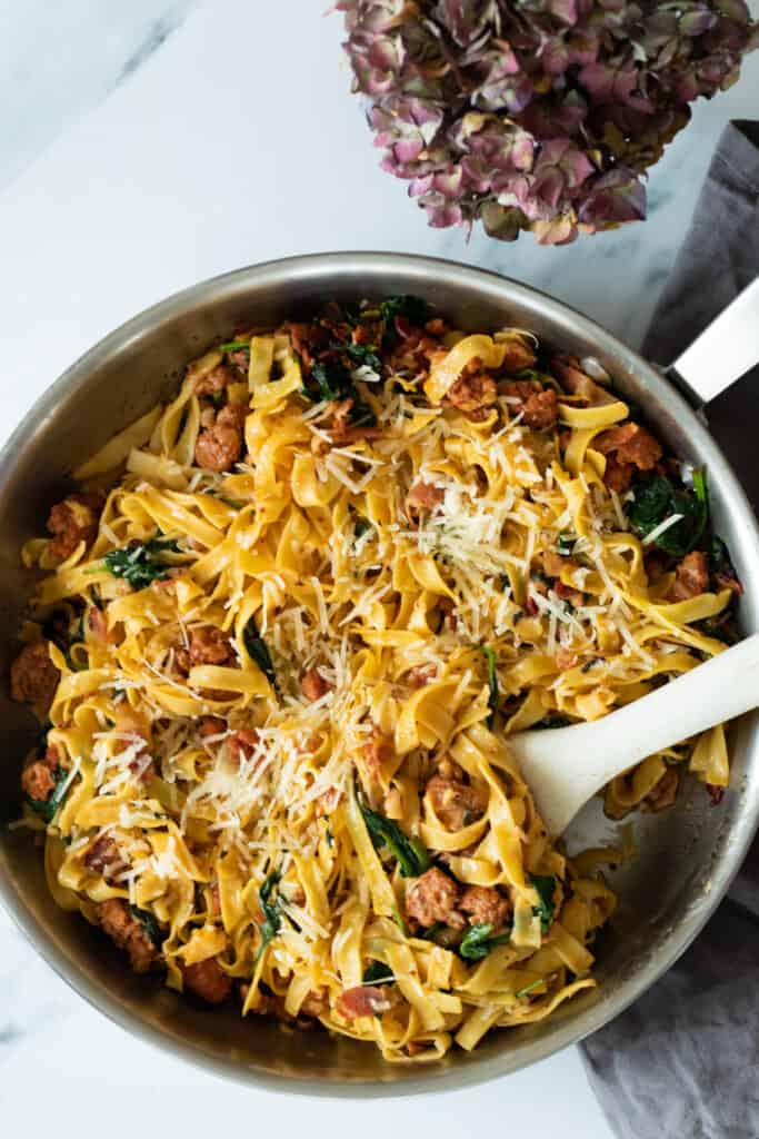 spicy sausage pasta in a pan with a wooden spoon