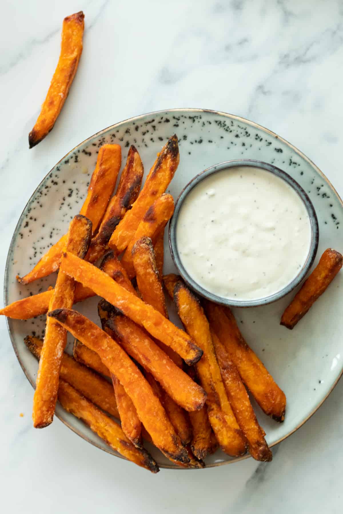 sweet potatoes on a plate next to a dipping sauce.