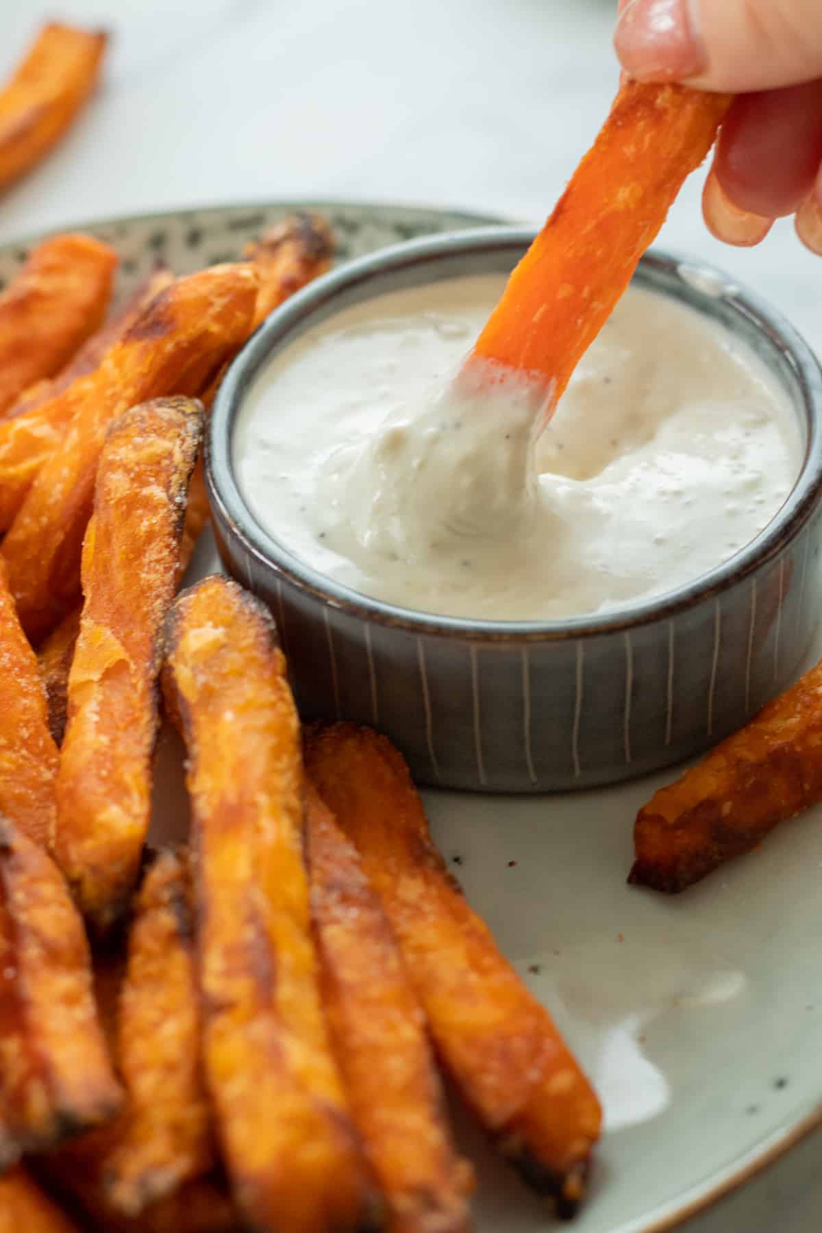 a sweet potato fry being dipped in blue cheese sauce.