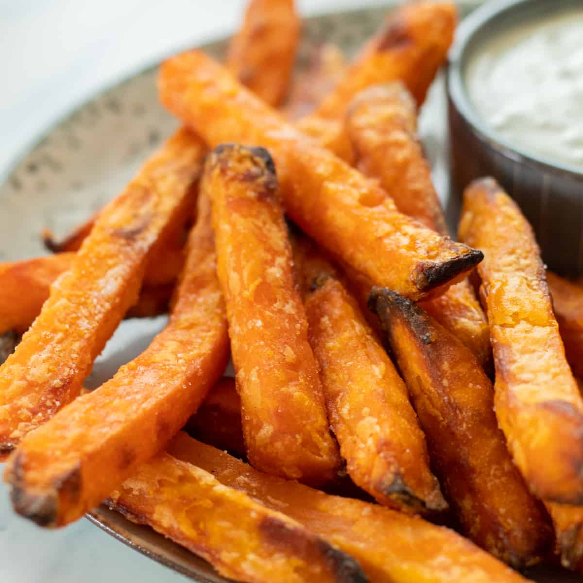 sweet potatoes on a plate next to a dipping sauce