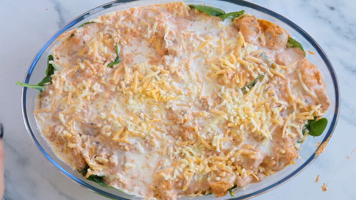 Buffalo chicken pasta bake topped with cheese before baking.