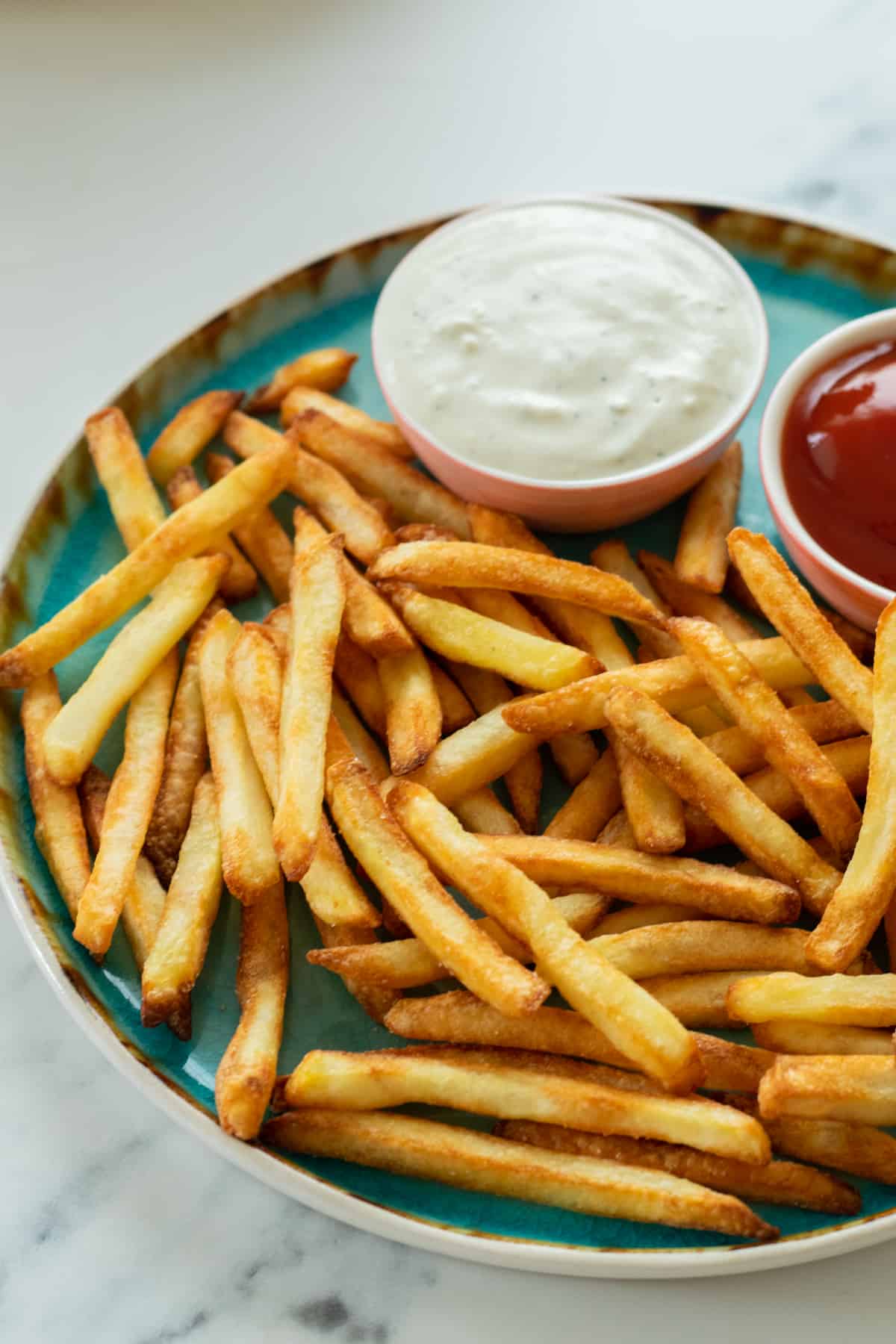 french fries on a plate with two dipping sauces.