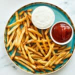 french fries on a plate with two dipping sauces