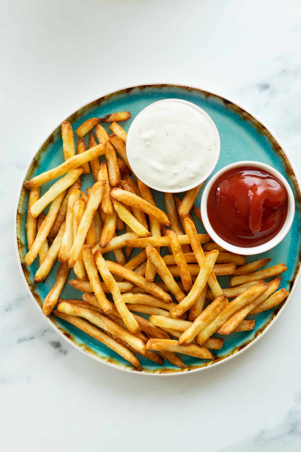 french fries on a plate with two dipping sauces