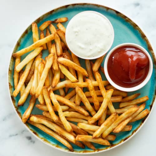 french fries on a plate with two dipping sauces