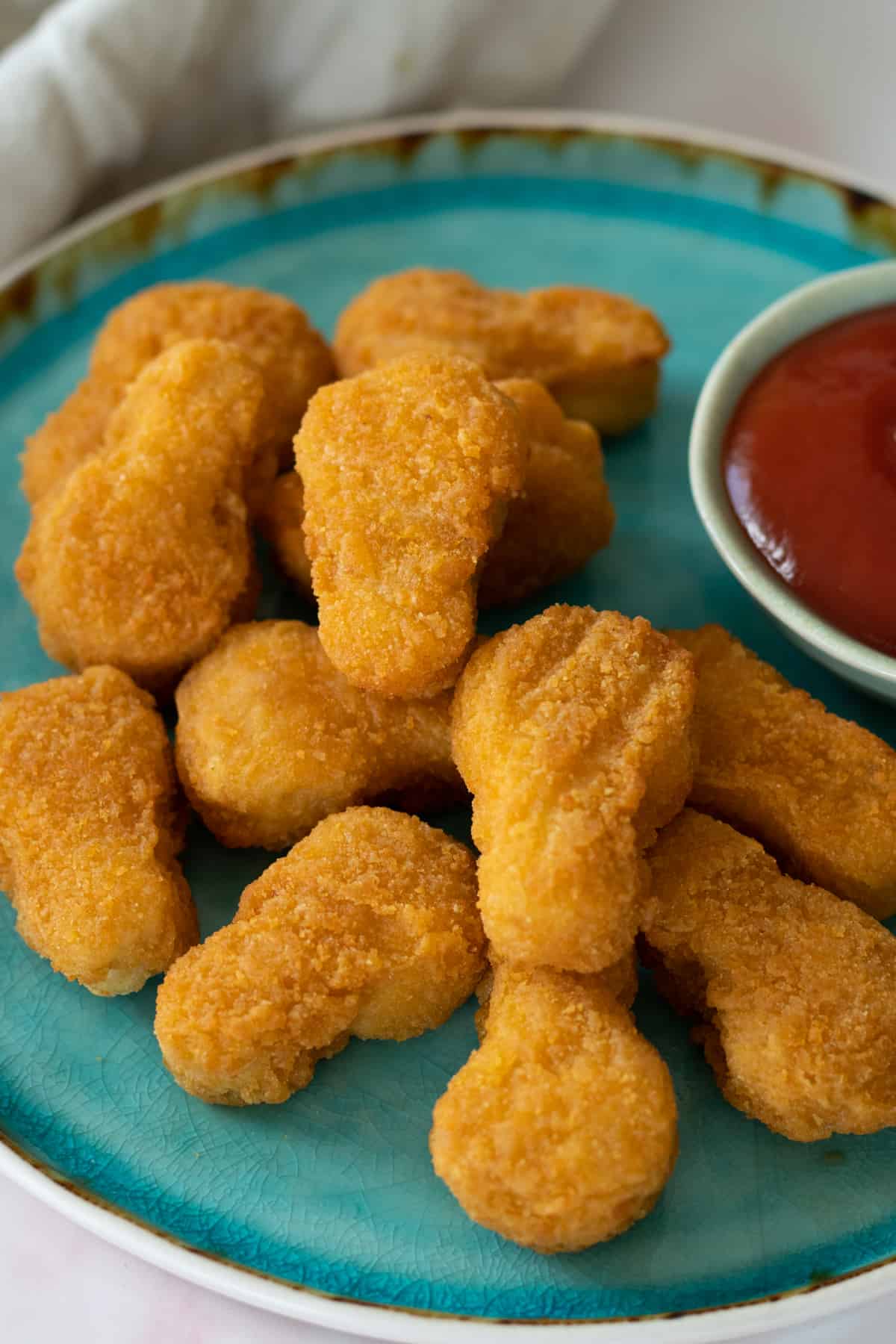 chicken nuggets on a plate with a bowl of ketchup.