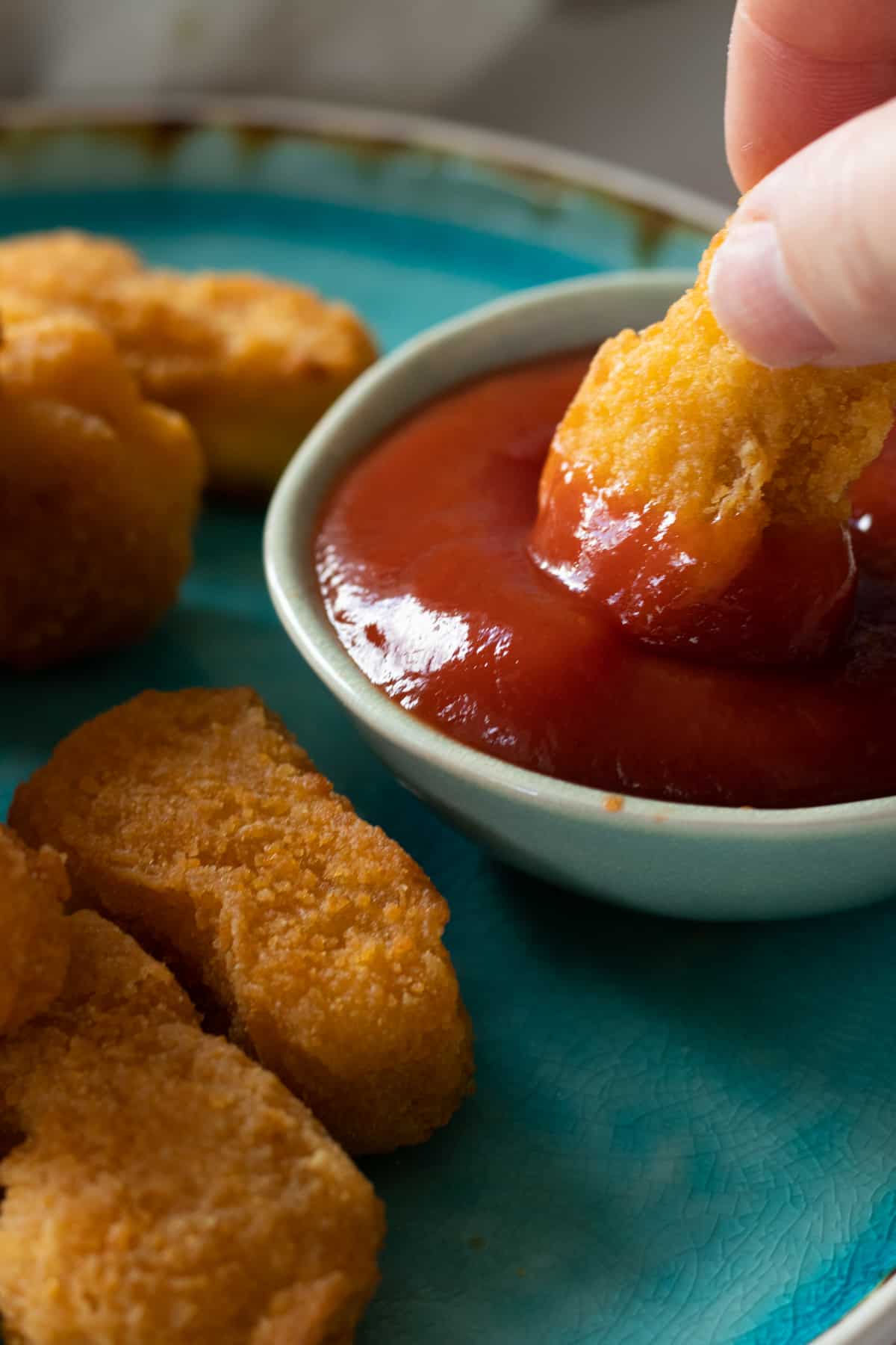 a chicken nugget being dipped in ketchup