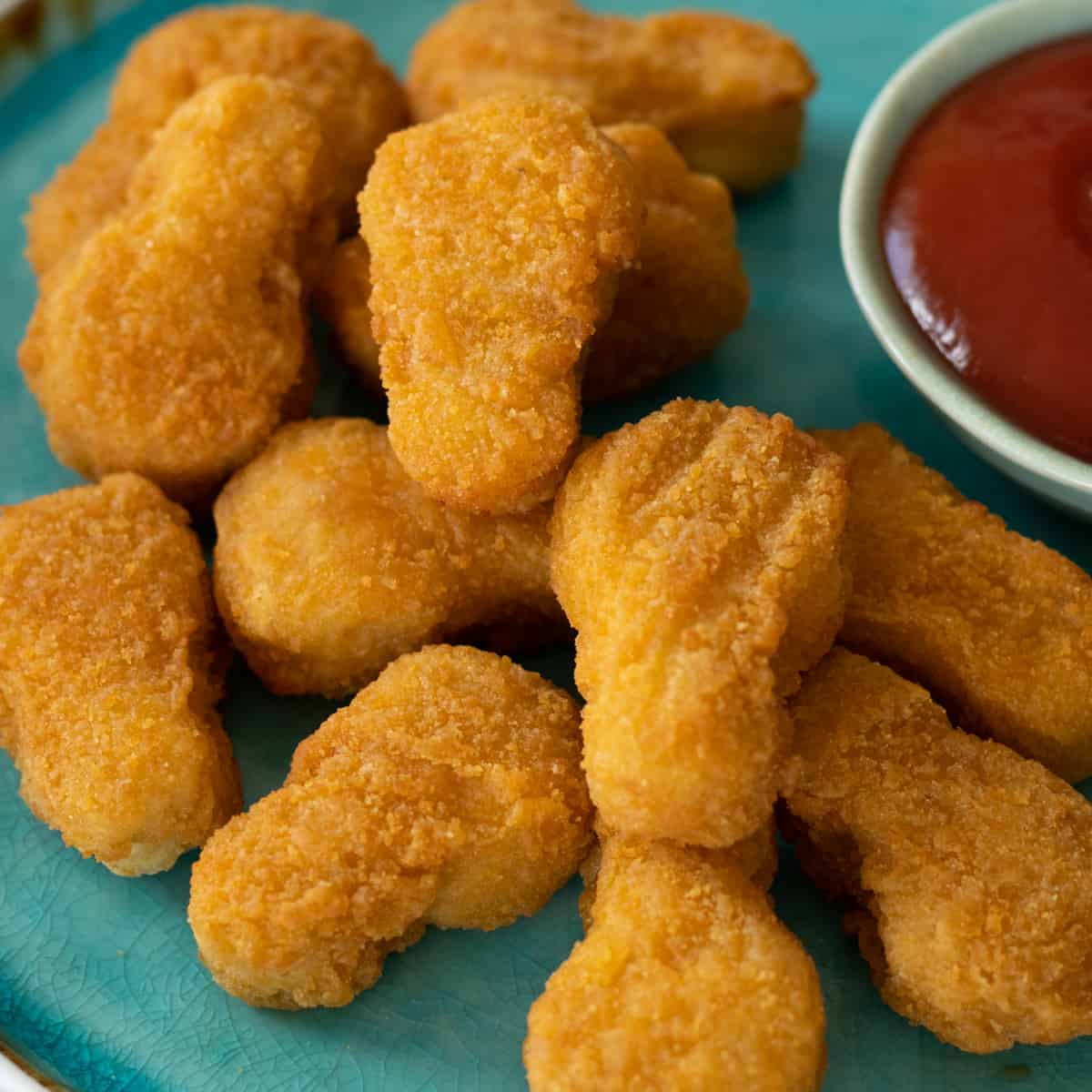 chicken nuggets on a plate with a bowl of ketchup