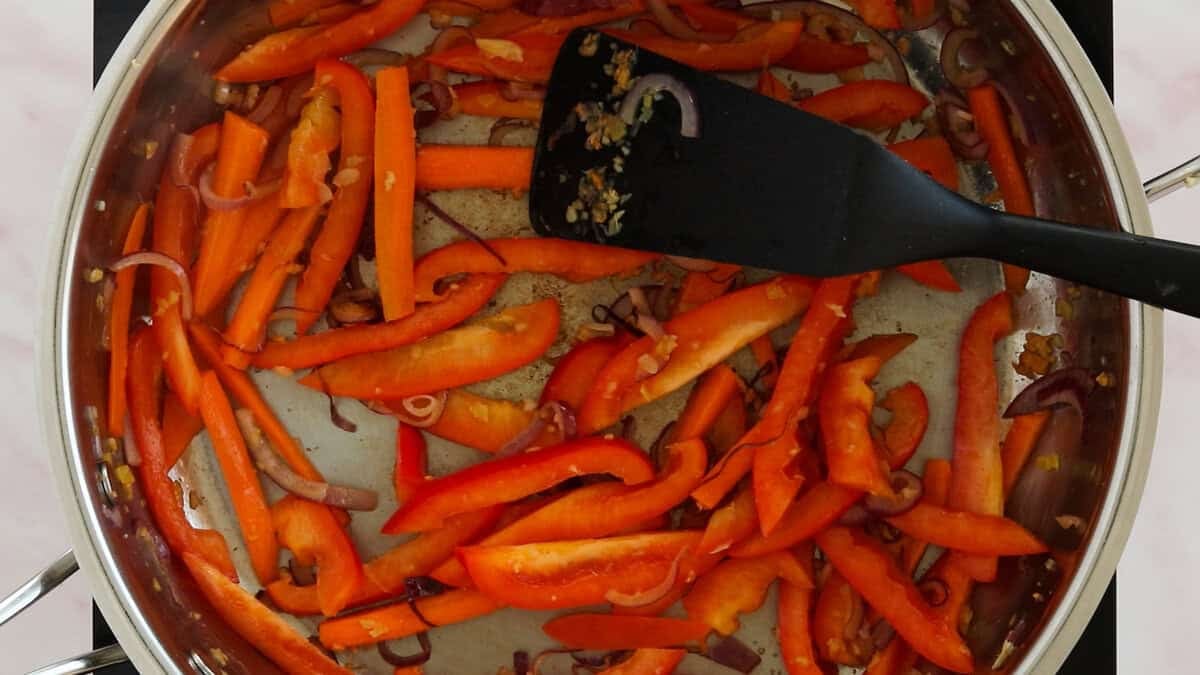 Stir-frying garlic, onion, carrots and red bell pepper to make shrimp mei fun.