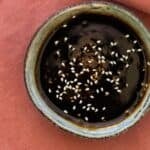 A bowl with hoemmade 3 ingredient teriyaki sauce topped with sesame seeds.