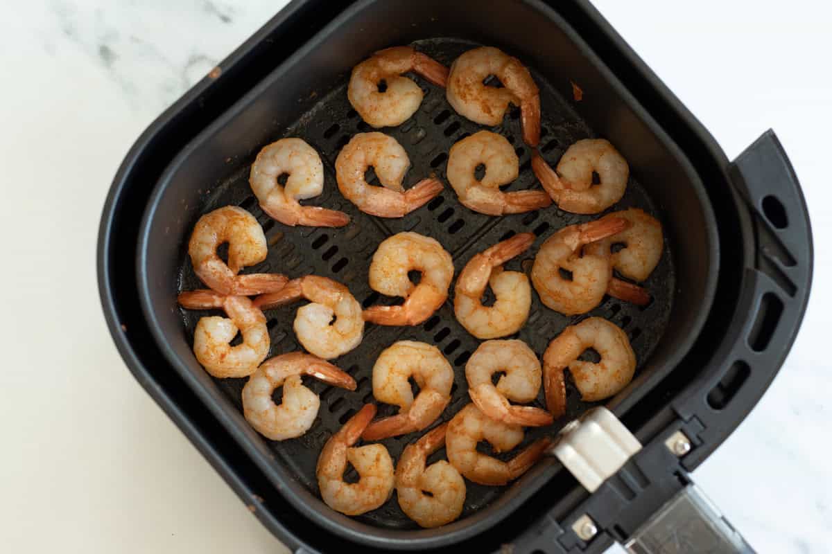 Frozen shrimp in an air fryer before thawing.