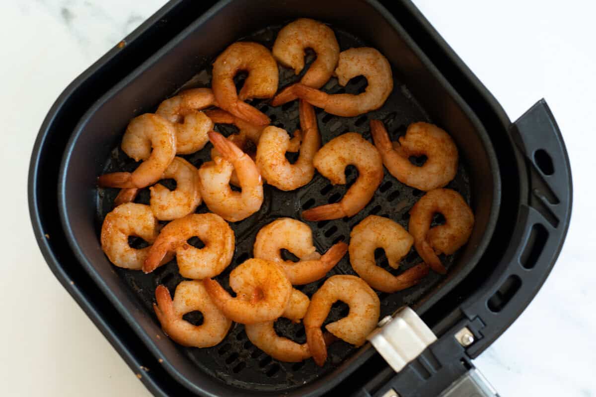 Seasoned shrimp in an air fryer before cooking.