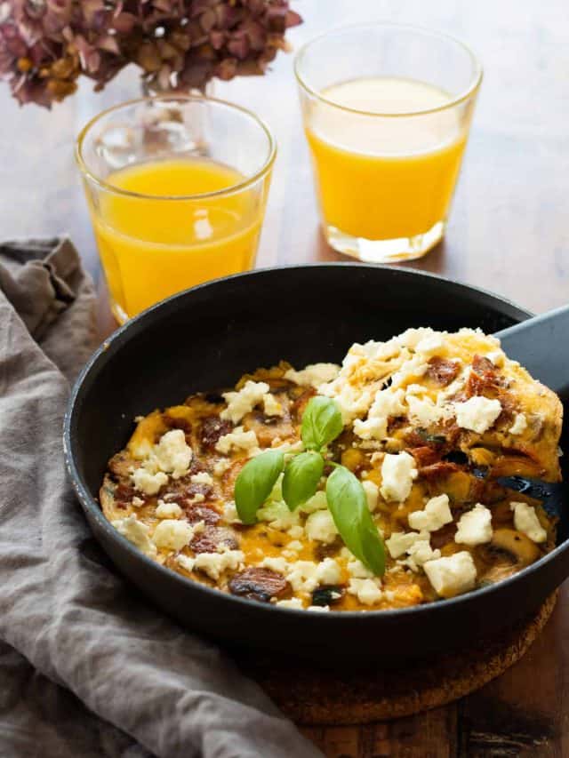 frittata in a pan with two glasses of orange juice next to it