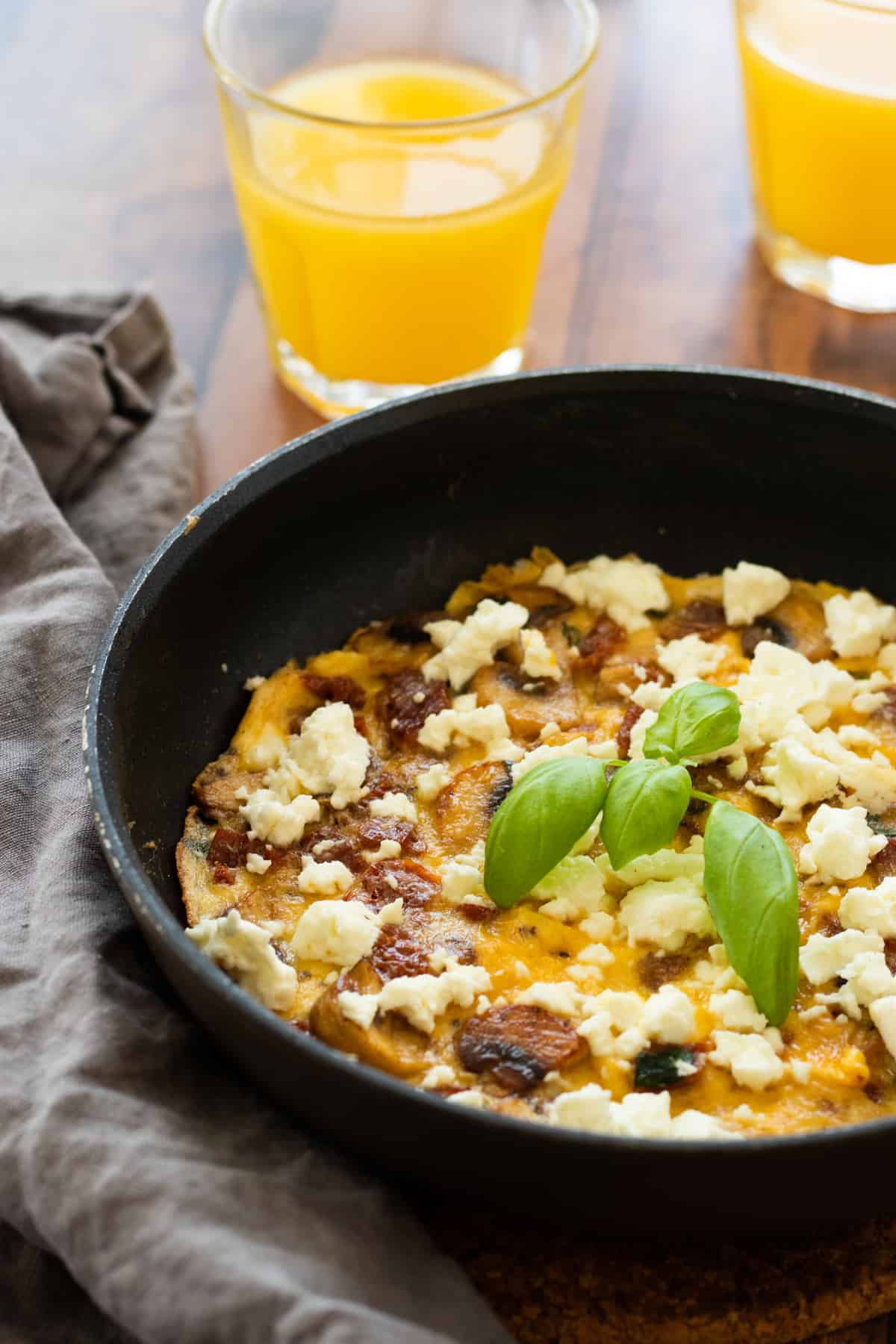 frittata in a pan with two glasses of orange juice next to it