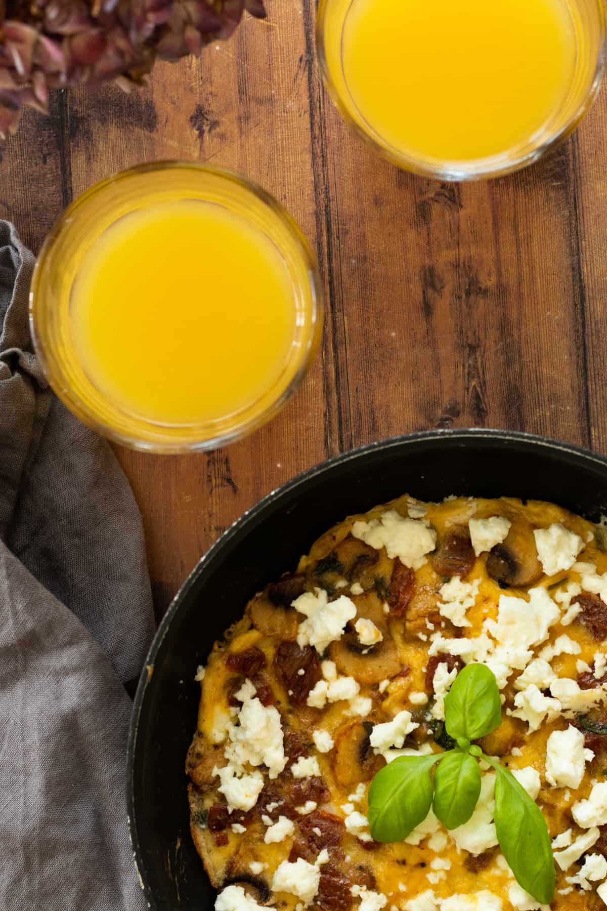 frittata in a pan with two glasses of orange juice next to it