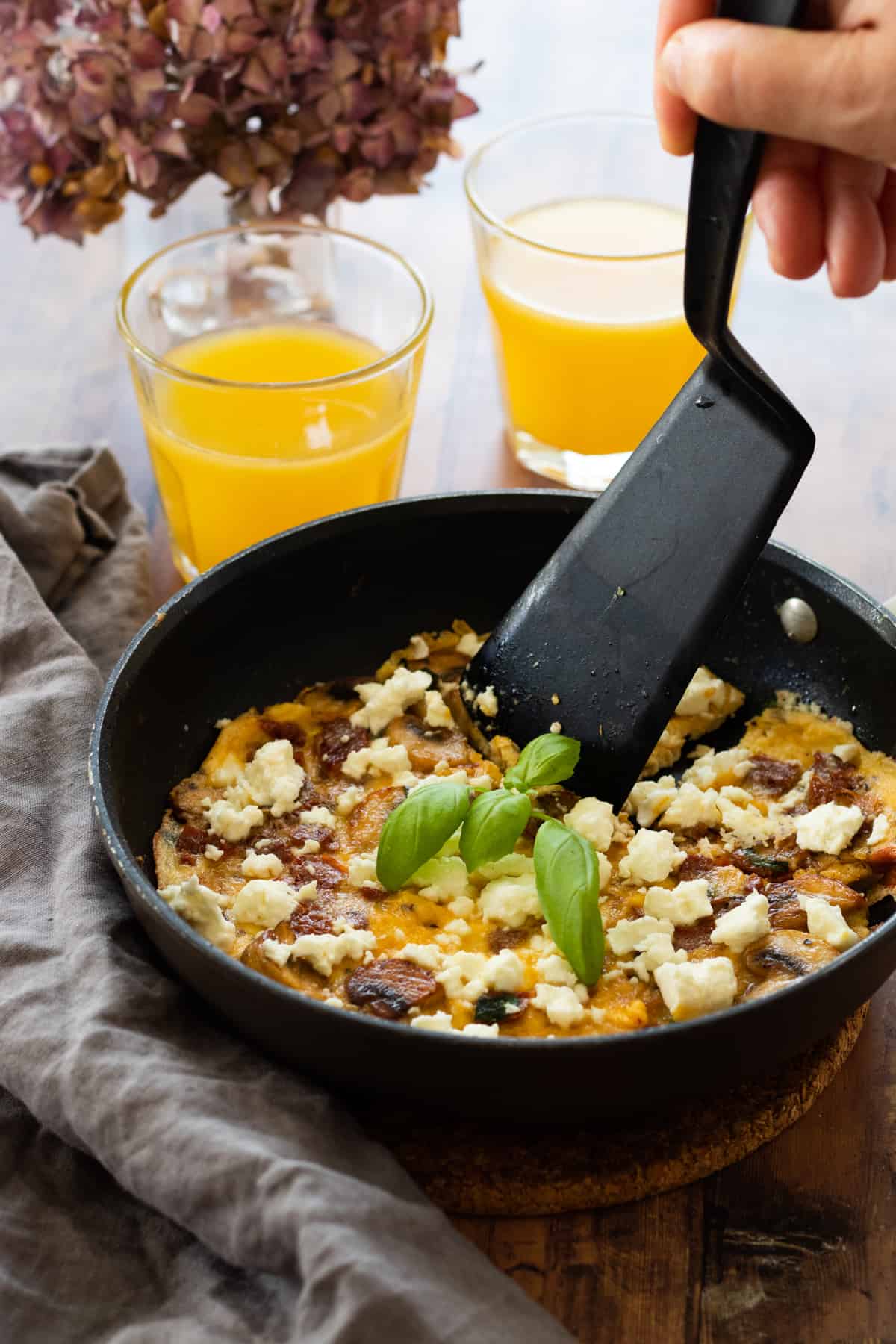 frittata in a pan with two glasses of orange juice next to it
