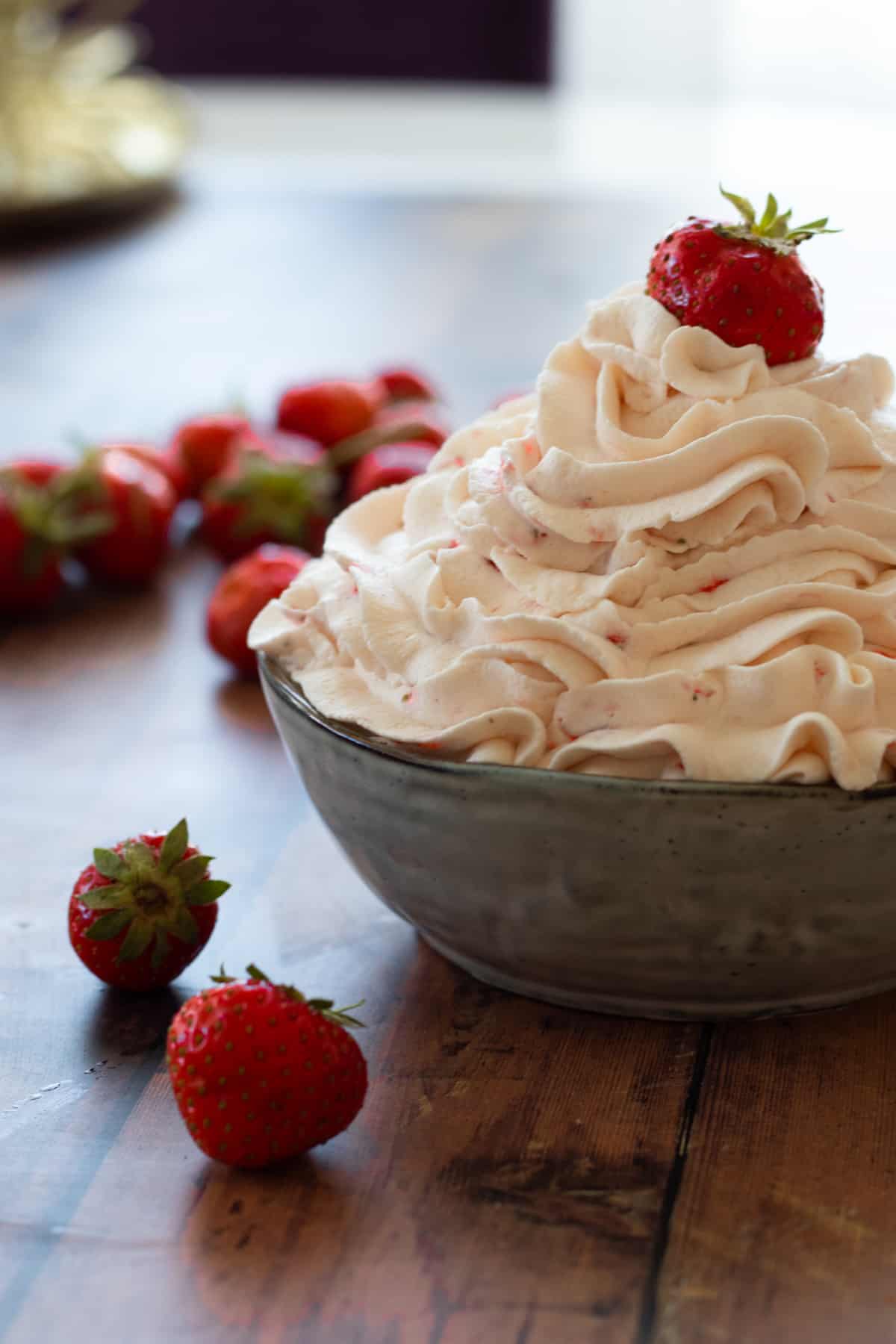 strawberry whipped cream in a bowl topped with a strawberry.