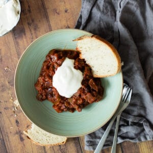 vegetarian chili sin carne on a green plate with crème fraîche and bread