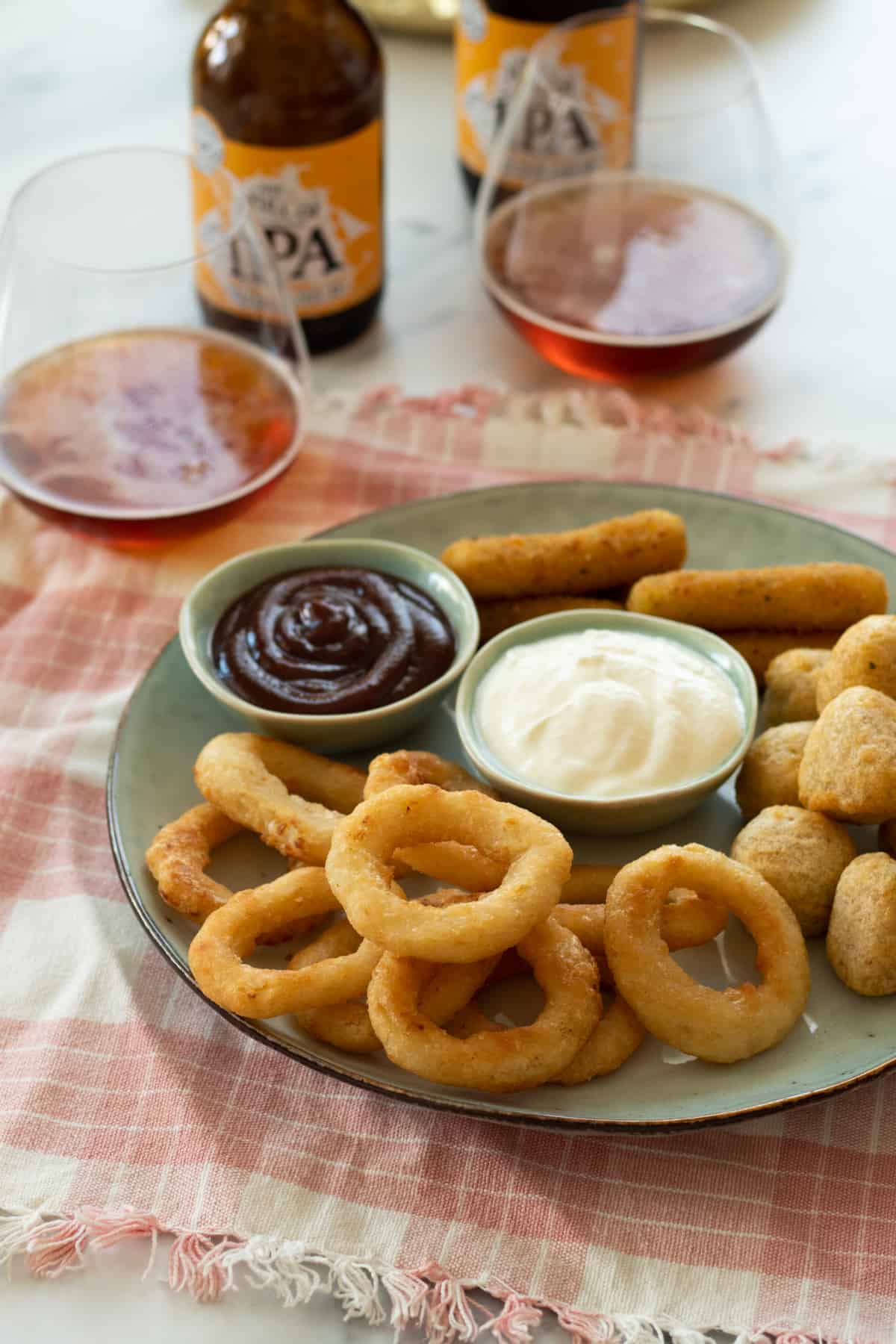 onion rings on a plate with dipping sauces and other appetizers.