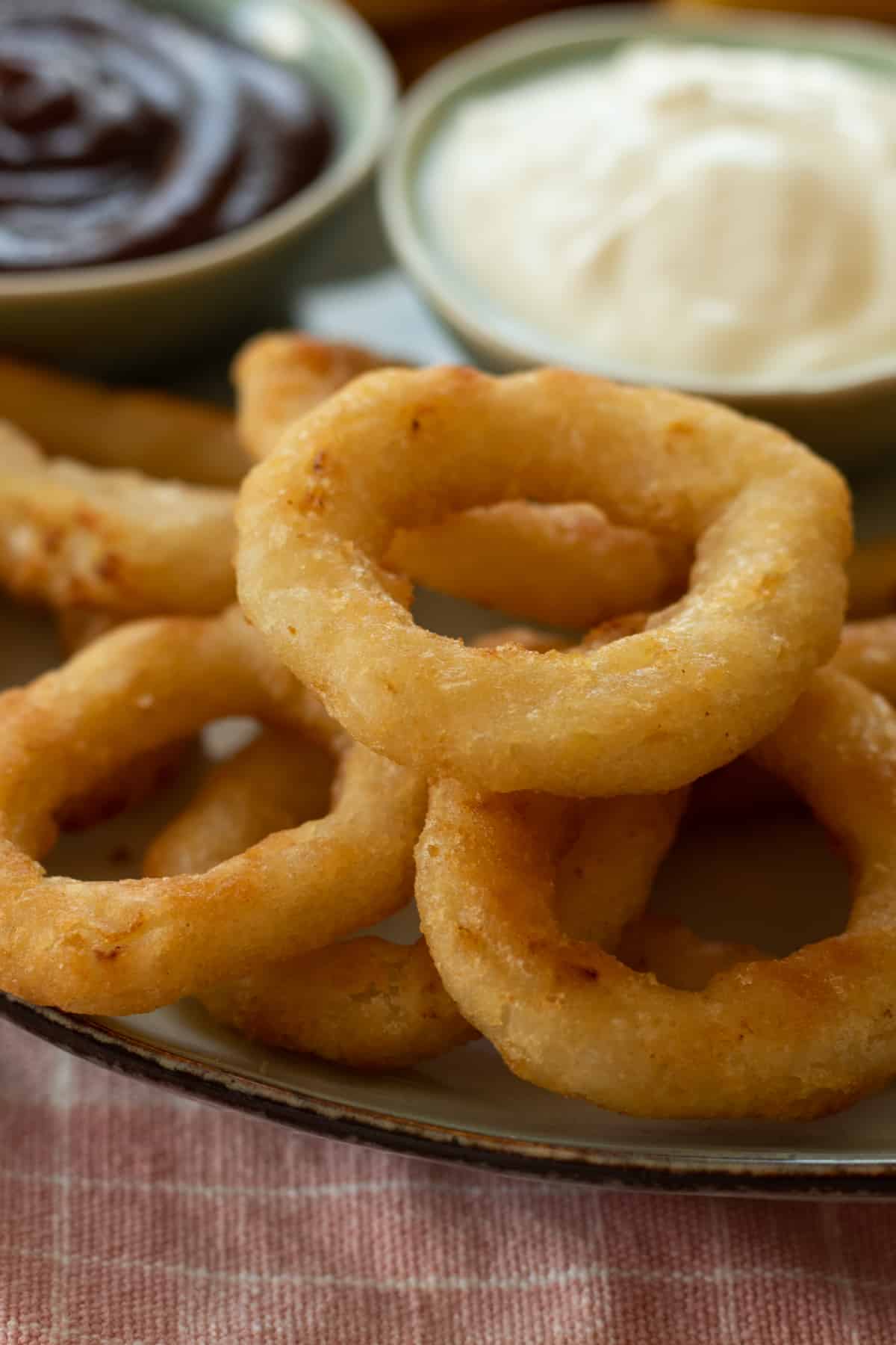onion rings on a plate with dipping sauces.