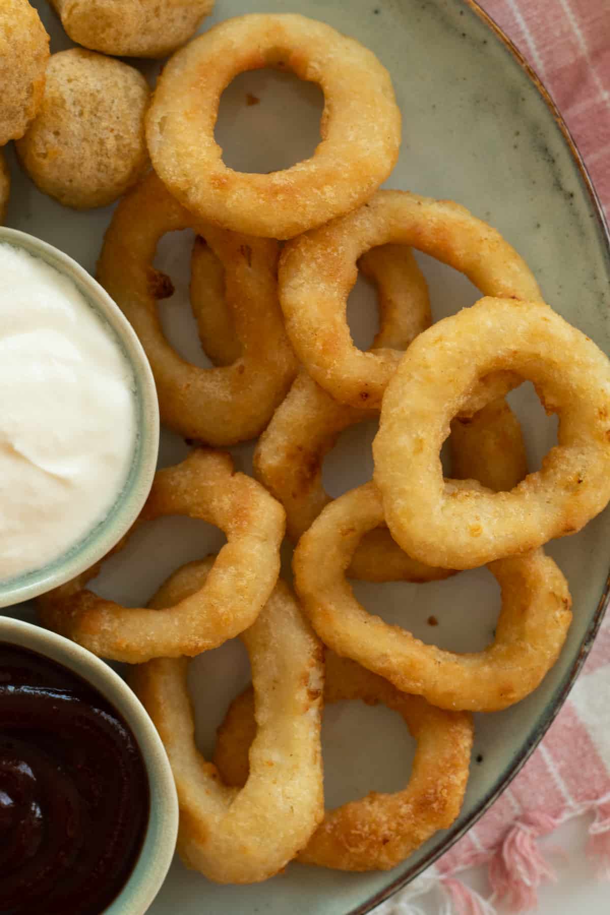 onion rings on a plate with dipping sauces.