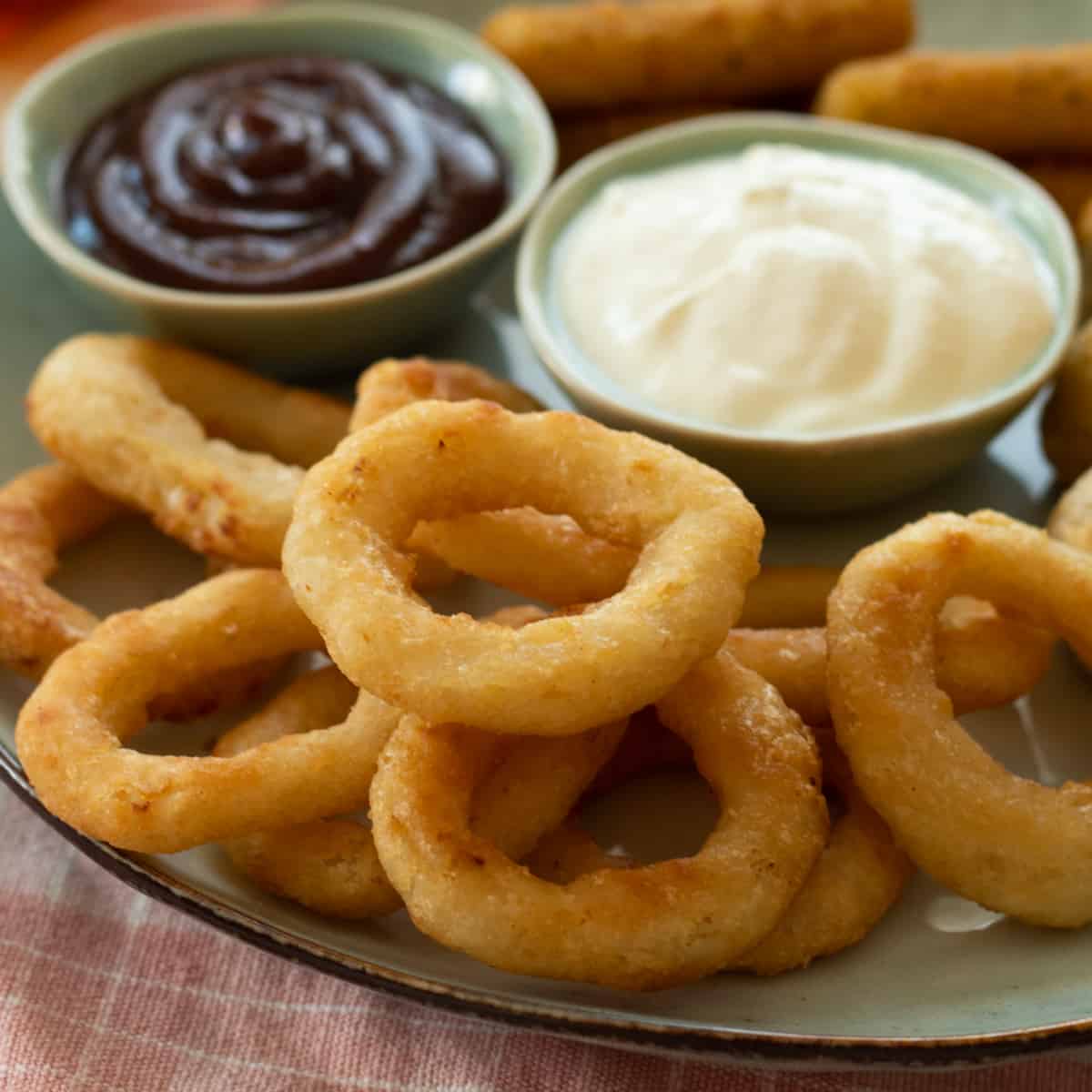 onion rings on a plate with dipping sauces.