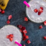 healthy strawberry banana smoothie with bananas and frozen starwberries around