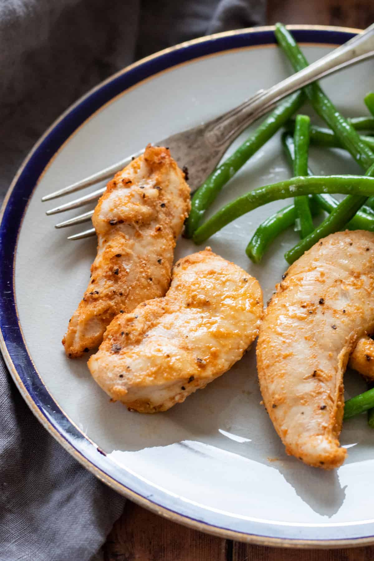 cooked chicken tenders on a plate with green beans
